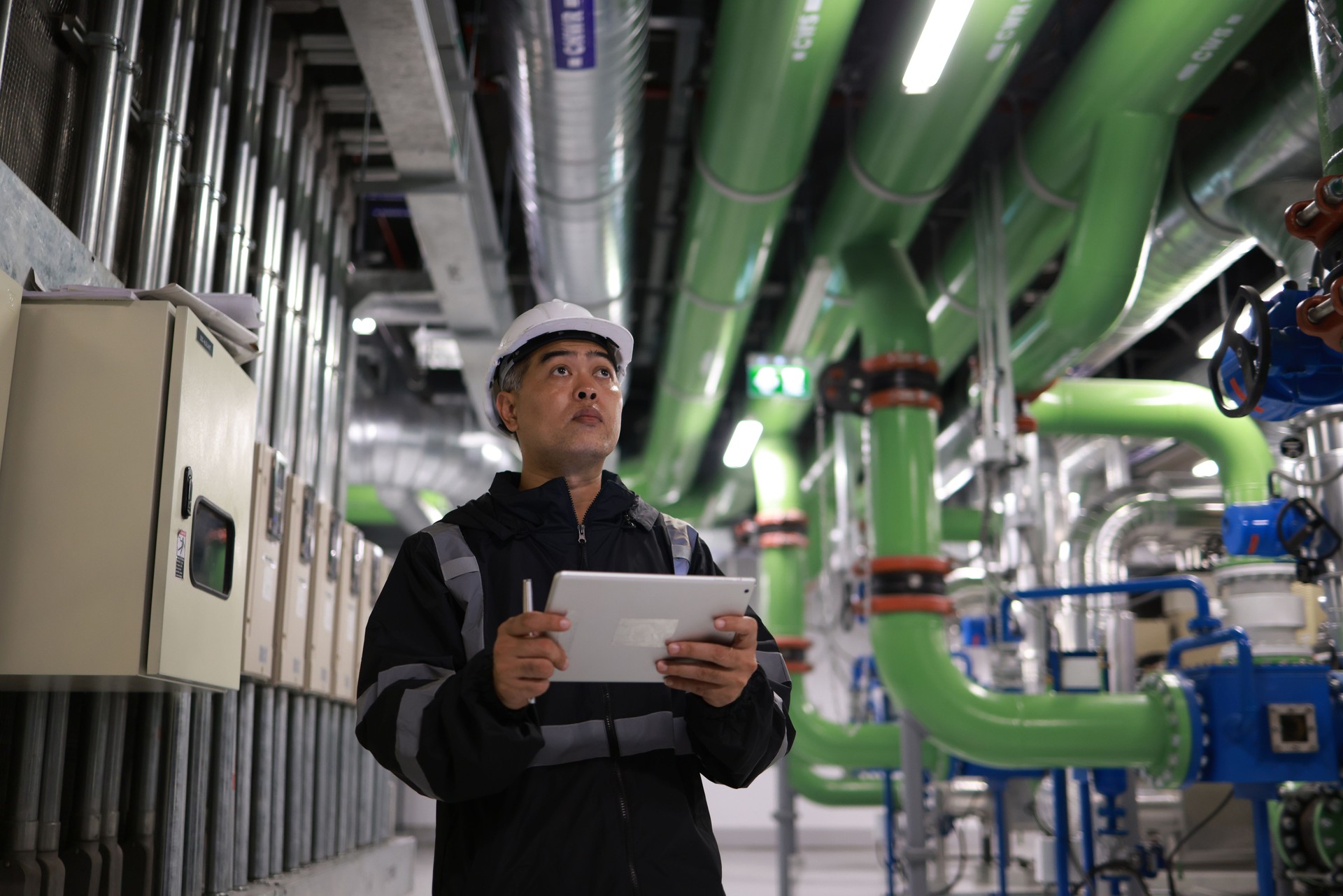 The male engineer  is working on a Cooling system pipeline  with a tablet